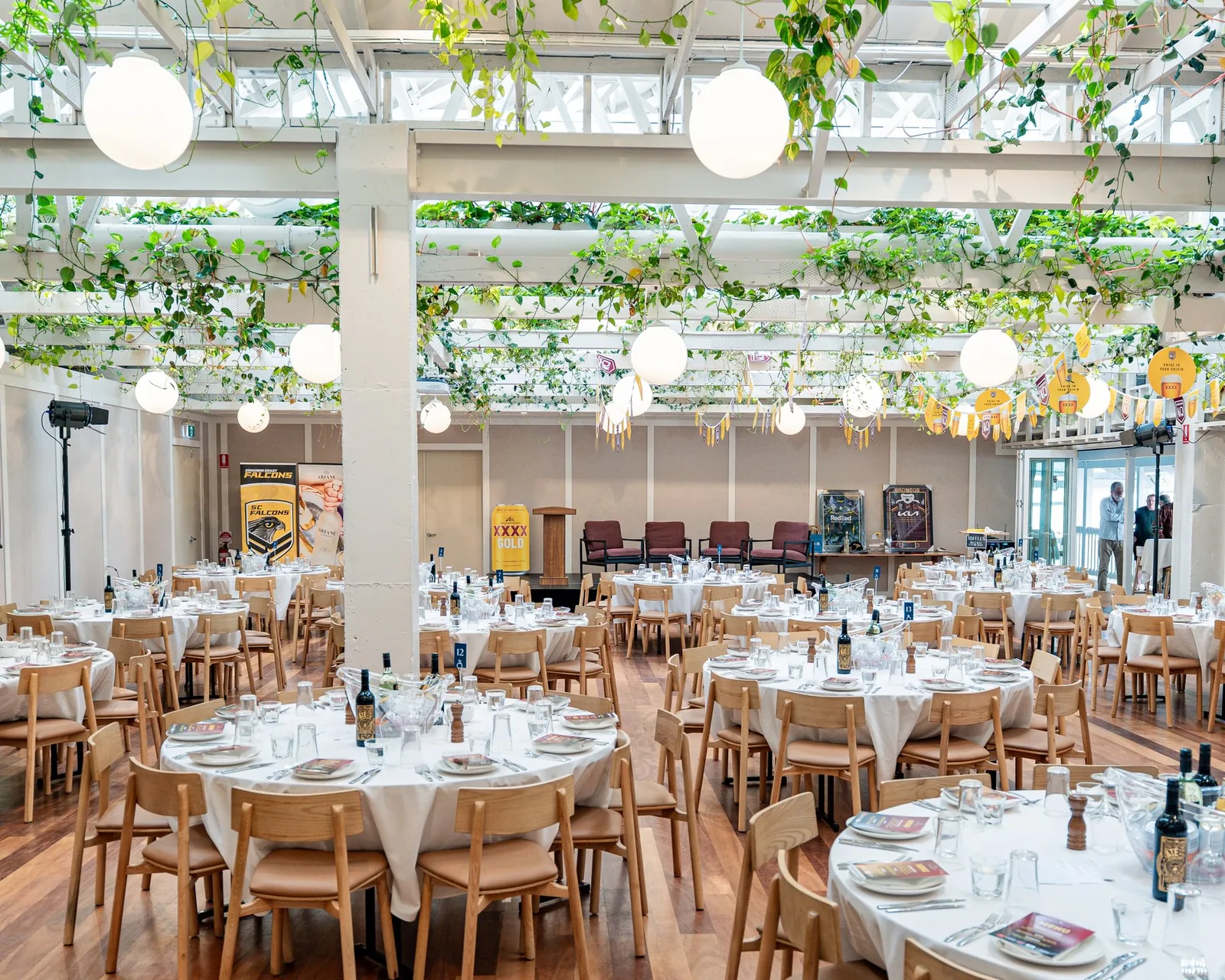 Wharf Events function room set for a seated lunch under hanging greenery