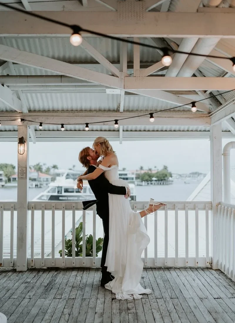 Groom lifting bride on the balcony overlooking the marina at Wharf Events